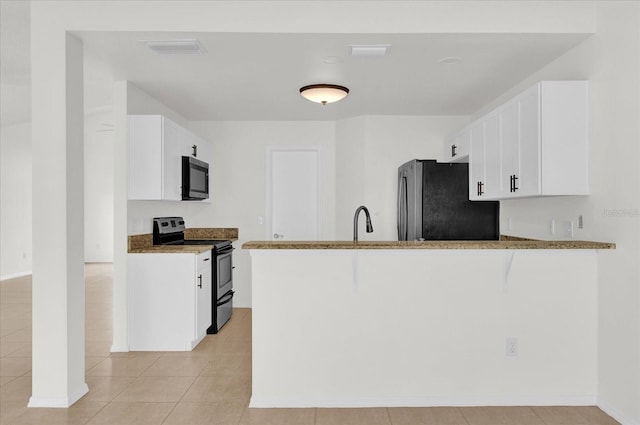 kitchen with kitchen peninsula, light stone countertops, white cabinets, and appliances with stainless steel finishes