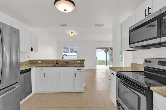 14646 Brightwell Ct, Orlando, FL 32824 - kitchen featuring appliances with stainless steel finishes, a sink, a peninsula, light tile patterned floors, and white cabinetry