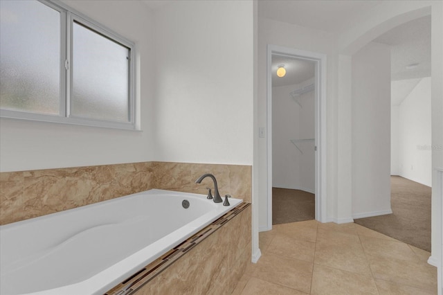 bathroom featuring a relaxing tiled tub and tile patterned flooring