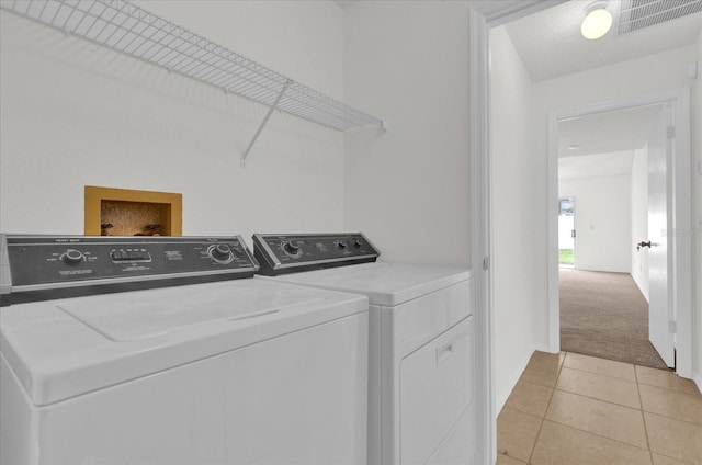 clothes washing area with light colored carpet and washer and dryer