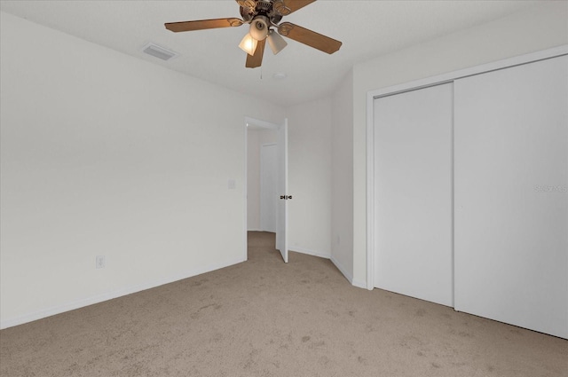 unfurnished bedroom with ceiling fan, light carpet, and a closet