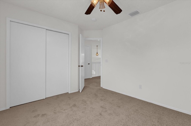 unfurnished bedroom featuring ceiling fan, light carpet, and a closet