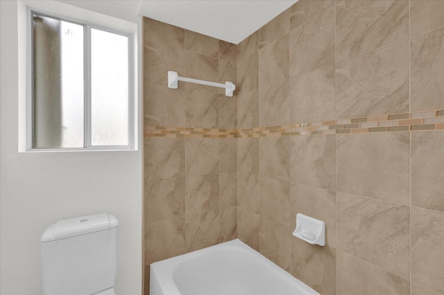 bathroom featuring tiled shower / bath combo and toilet