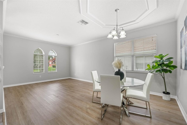 dining room with a chandelier, light wood-type flooring, and ornamental molding