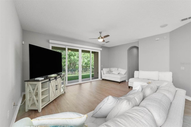 living room with light wood-type flooring, a textured ceiling, and ceiling fan