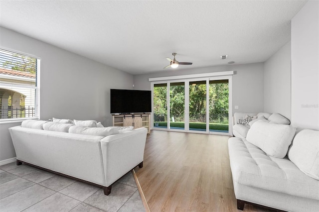 living room with ceiling fan, a textured ceiling, hardwood / wood-style flooring, and a healthy amount of sunlight