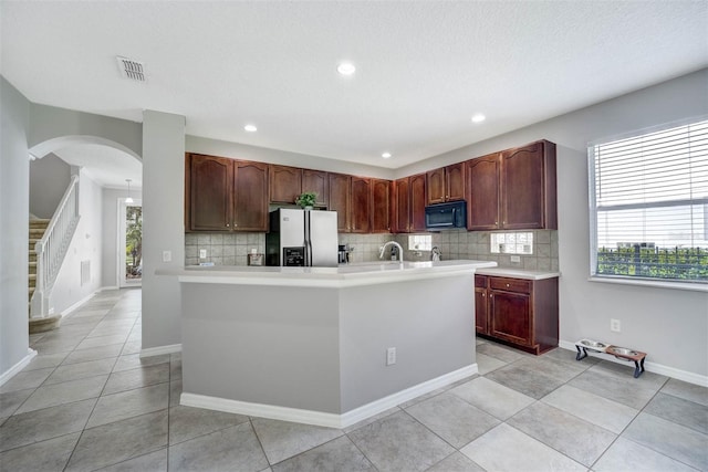 kitchen featuring a textured ceiling, decorative backsplash, a healthy amount of sunlight, and stainless steel fridge