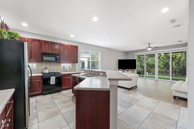 kitchen featuring a center island with sink, black appliances, sink, ceiling fan, and light wood-type flooring