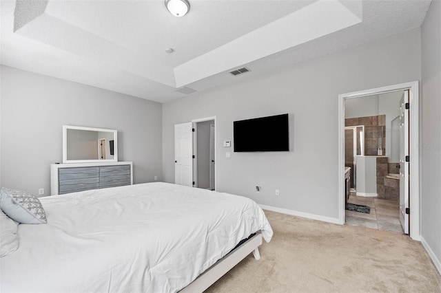 carpeted bedroom featuring a textured ceiling and ensuite bath