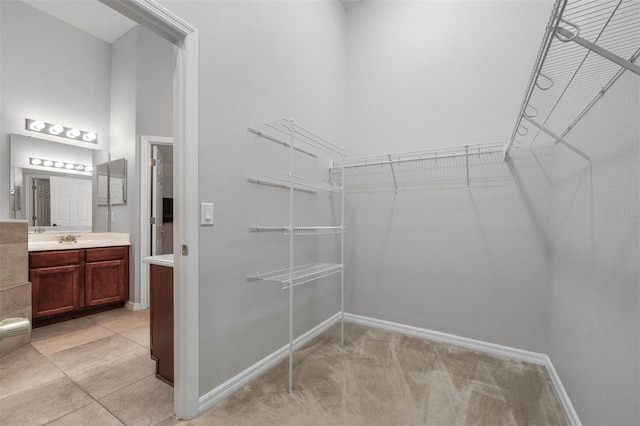 walk in closet featuring sink and light colored carpet