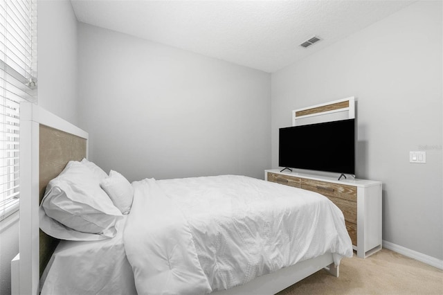 bedroom with light colored carpet and a textured ceiling