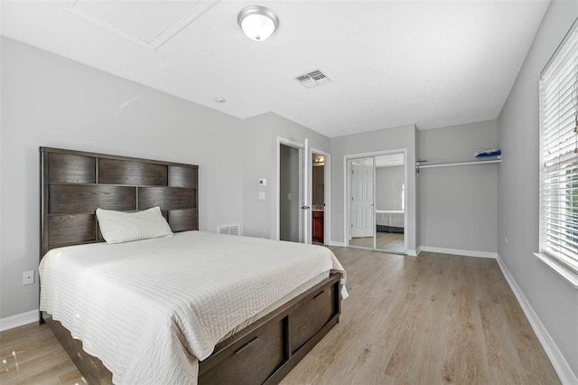 bedroom featuring connected bathroom, a closet, and light hardwood / wood-style flooring