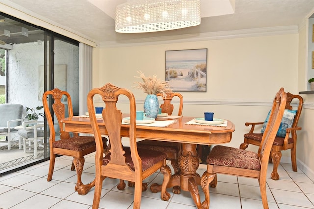 dining space with light tile patterned floors, ornamental molding, and an inviting chandelier