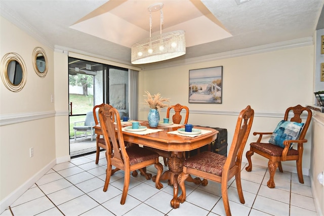 dining space with a raised ceiling, crown molding, and light tile patterned flooring