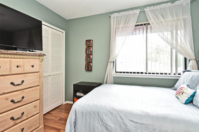 bedroom featuring a textured ceiling, a closet, and dark wood-type flooring