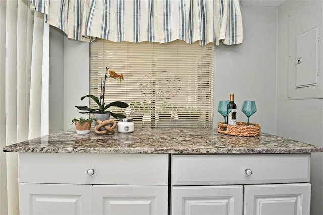 kitchen featuring light stone countertops, white cabinetry, and electric panel