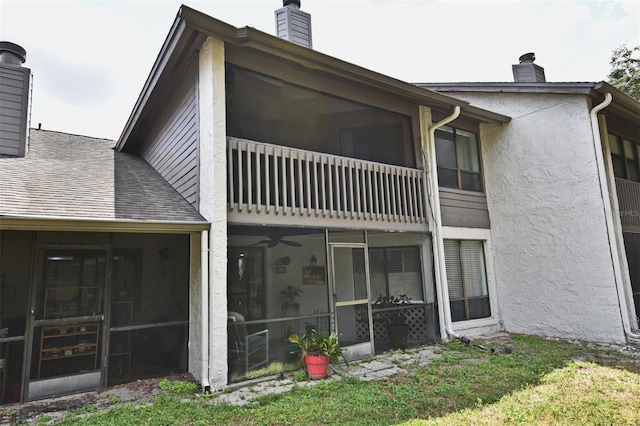 back of property featuring a balcony, a lawn, and a sunroom