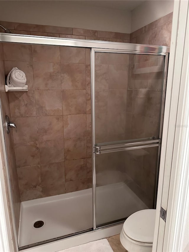 bathroom featuring a shower with door and toilet