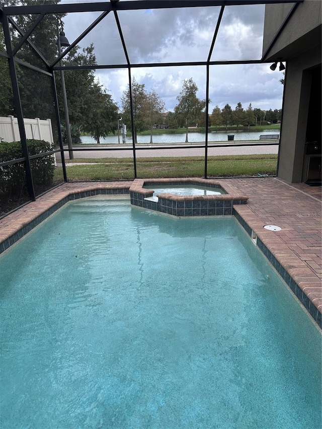 view of pool featuring glass enclosure, an in ground hot tub, and a water view