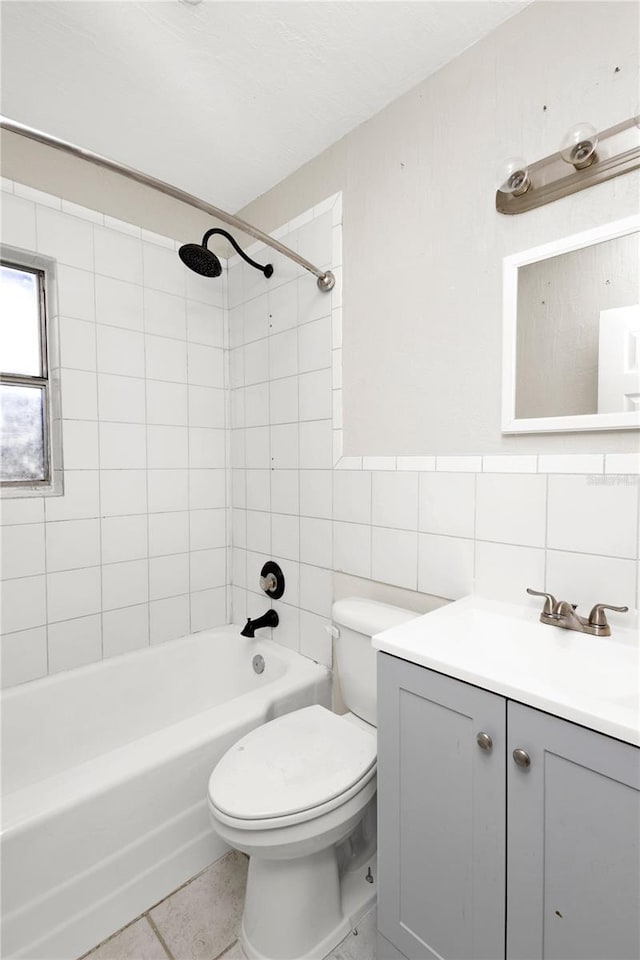 full bathroom with tiled shower / bath, vanity, tile patterned floors, toilet, and tile walls