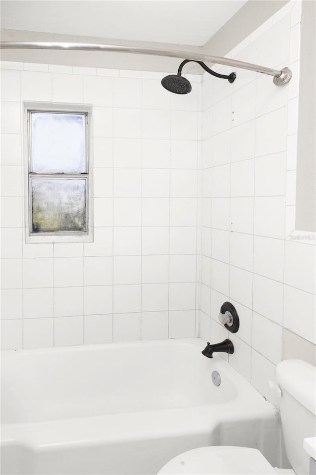 bathroom with toilet and tiled shower / bath combo