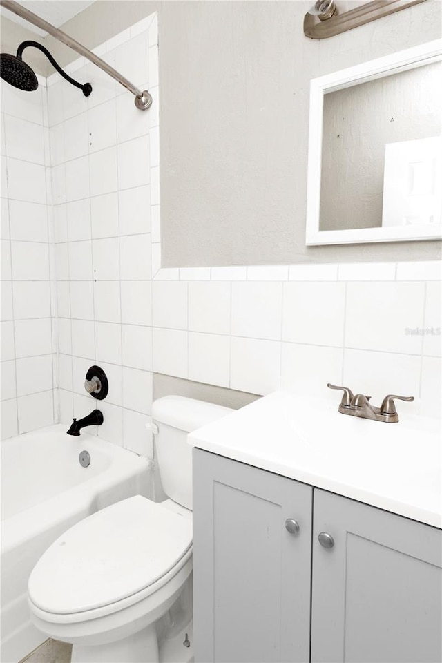 full bathroom featuring tile walls, vanity, toilet, and tiled shower / bath