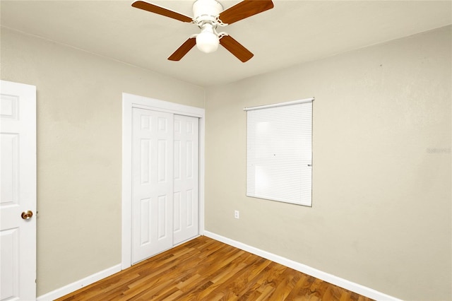 unfurnished bedroom featuring a closet, hardwood / wood-style floors, and ceiling fan