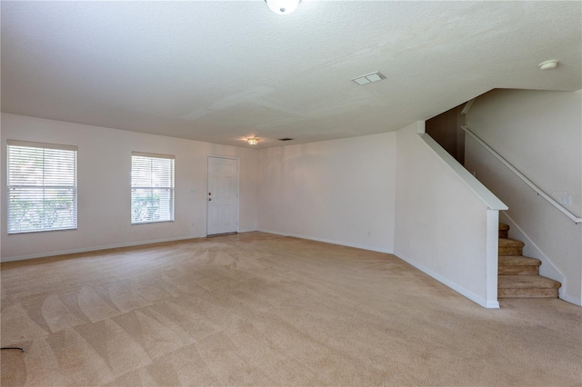 interior space with a textured ceiling and light carpet