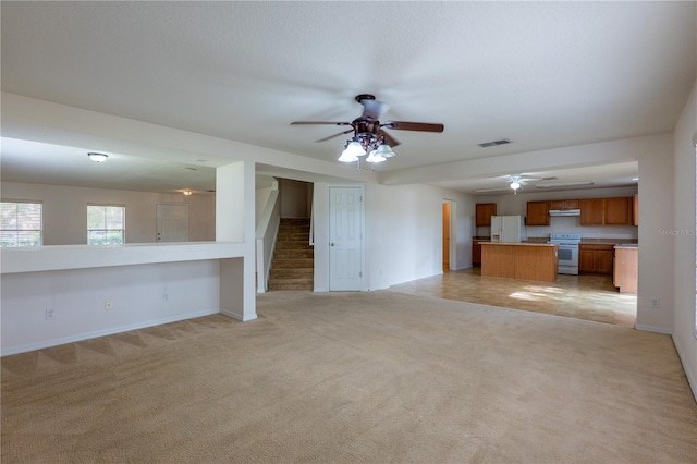 unfurnished living room featuring ceiling fan and light carpet