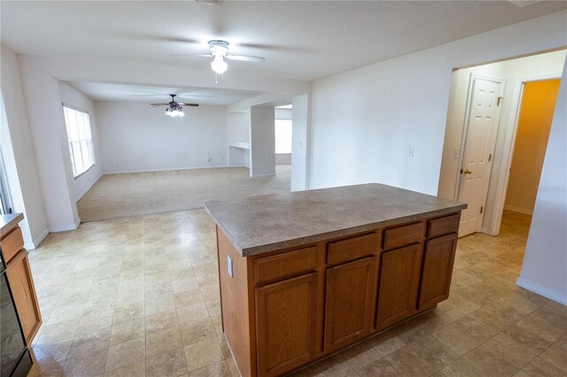 kitchen featuring a kitchen island, a textured ceiling, light colored carpet, and ceiling fan