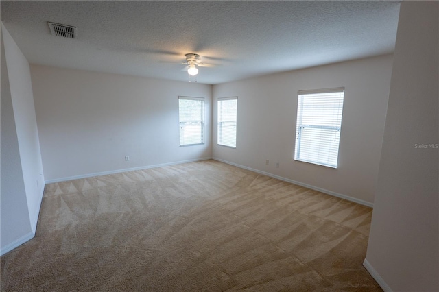 empty room featuring ceiling fan, a textured ceiling, and light carpet