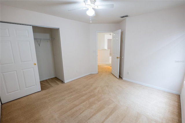 unfurnished bedroom with ceiling fan, light carpet, and a closet