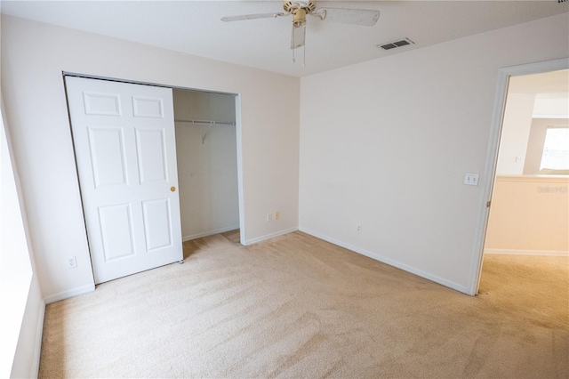 unfurnished bedroom with ceiling fan, light carpet, and a closet