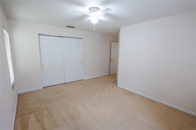 unfurnished bedroom with light carpet, ceiling fan, and a closet