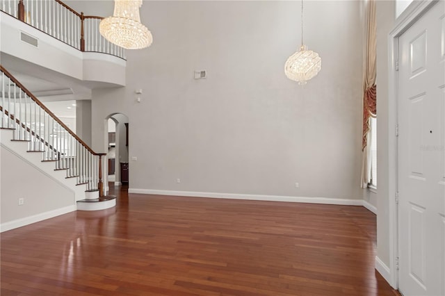 entrance foyer with dark wood-type flooring, an inviting chandelier, and a towering ceiling