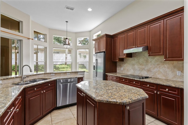 kitchen with stainless steel appliances, a kitchen island, light tile patterned floors, hanging light fixtures, and sink