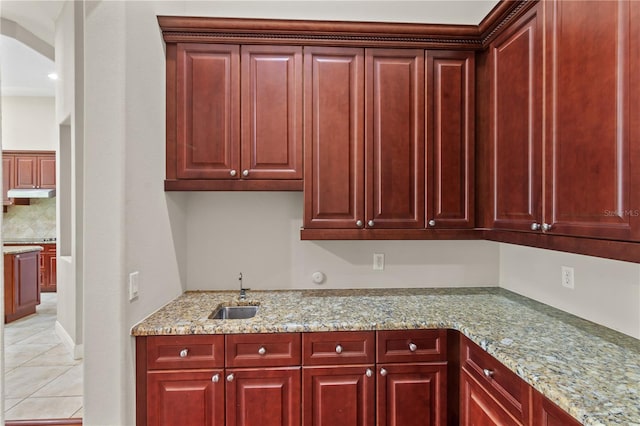 kitchen with light tile patterned floors, sink, and light stone countertops