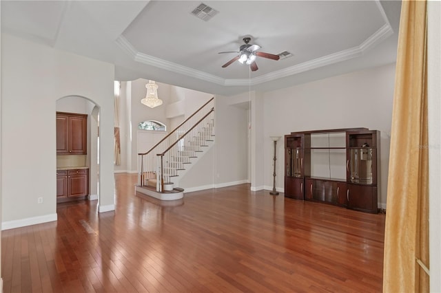 unfurnished living room featuring dark wood-type flooring, ornamental molding, and ceiling fan