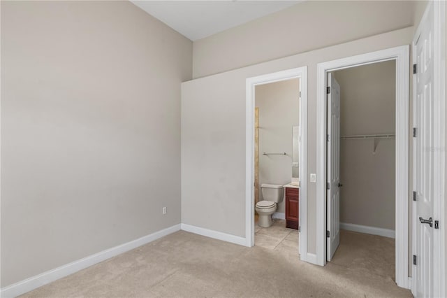 unfurnished bedroom with light carpet, ensuite bath, a closet, and a spacious closet