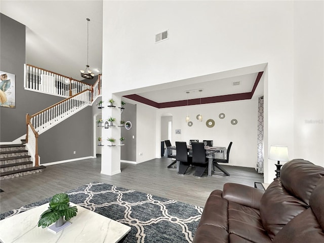 living room featuring dark hardwood / wood-style floors, a chandelier, and a high ceiling