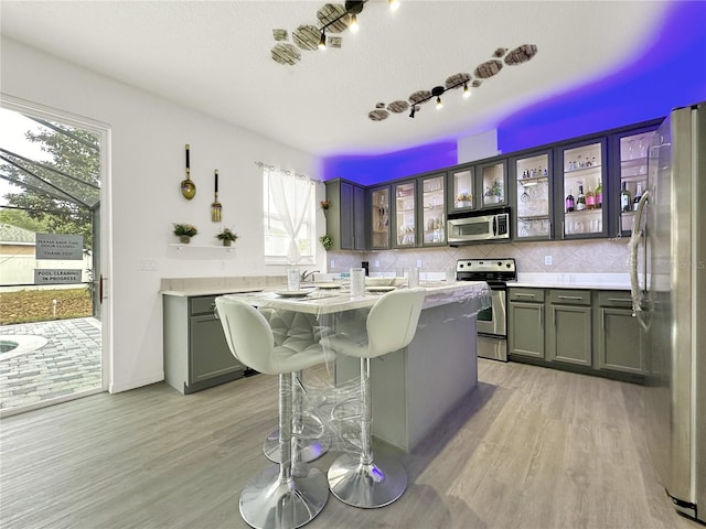 kitchen with tasteful backsplash, light wood-type flooring, stainless steel appliances, and a kitchen island