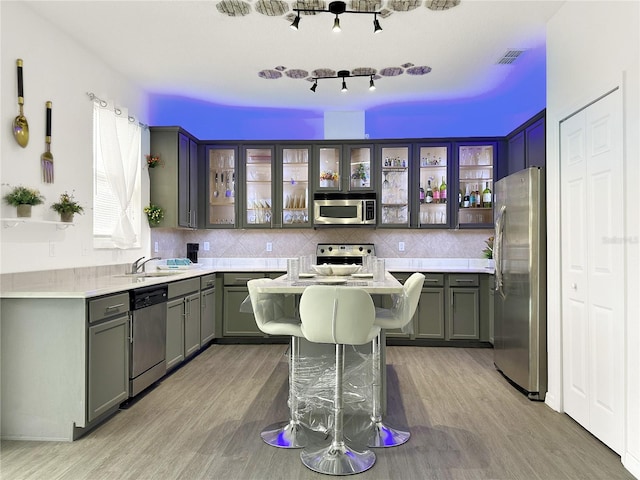 kitchen featuring tasteful backsplash, light hardwood / wood-style floors, a center island, and appliances with stainless steel finishes