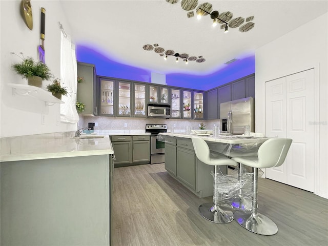 kitchen with a kitchen island, appliances with stainless steel finishes, sink, backsplash, and a kitchen bar