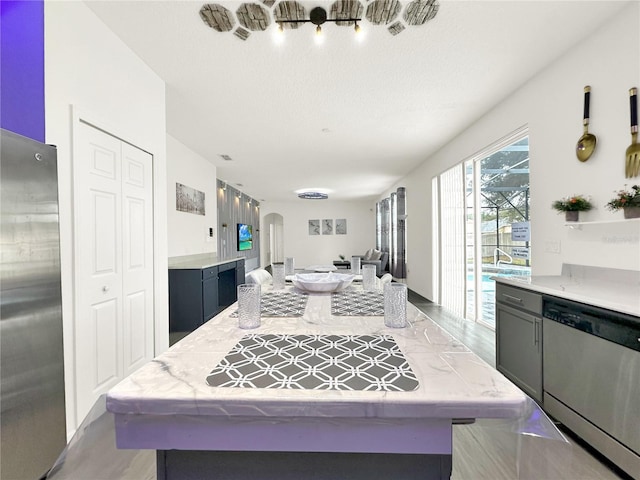 kitchen with light wood-type flooring, a textured ceiling, and appliances with stainless steel finishes