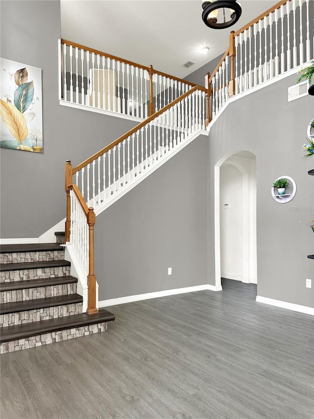 staircase featuring wood-type flooring and a high ceiling