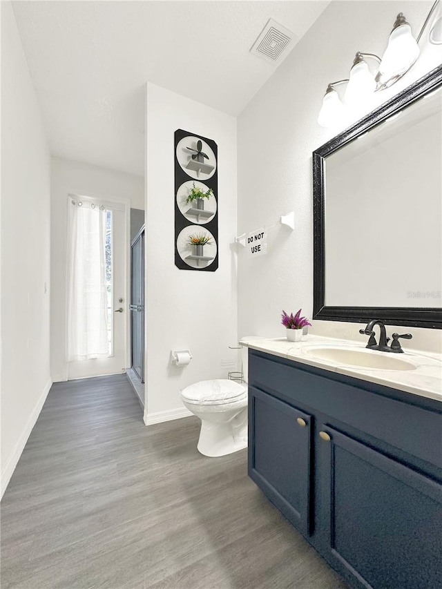 bathroom featuring vanity, toilet, a shower with door, and hardwood / wood-style floors