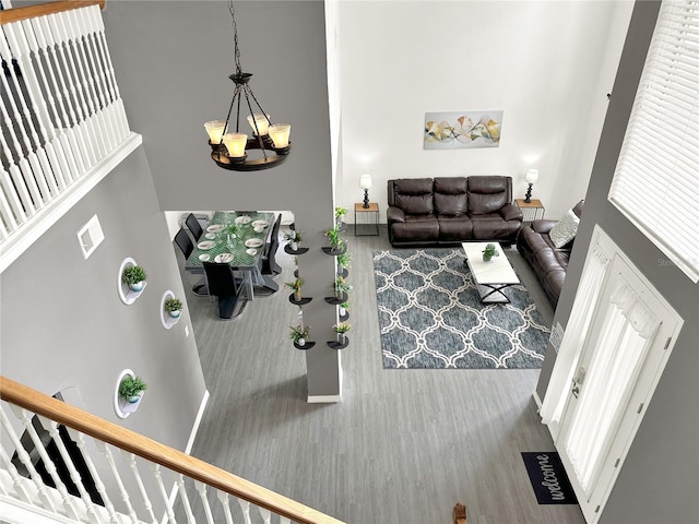 living room featuring a towering ceiling, wood-type flooring, and a chandelier