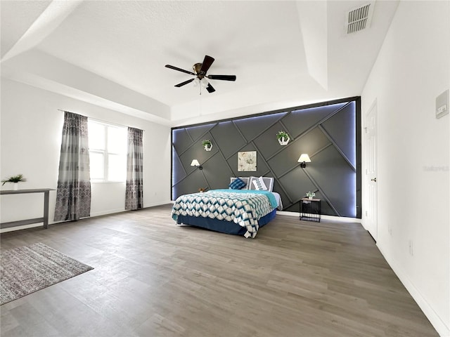 bedroom featuring ceiling fan, a tray ceiling, and hardwood / wood-style floors