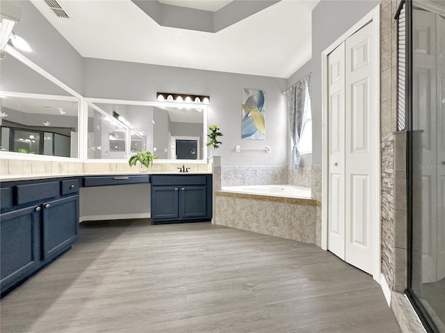 bathroom with vanity, wood-type flooring, and plus walk in shower