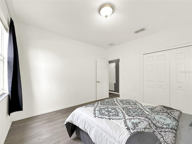 bedroom with dark hardwood / wood-style floors, a closet, and a textured ceiling